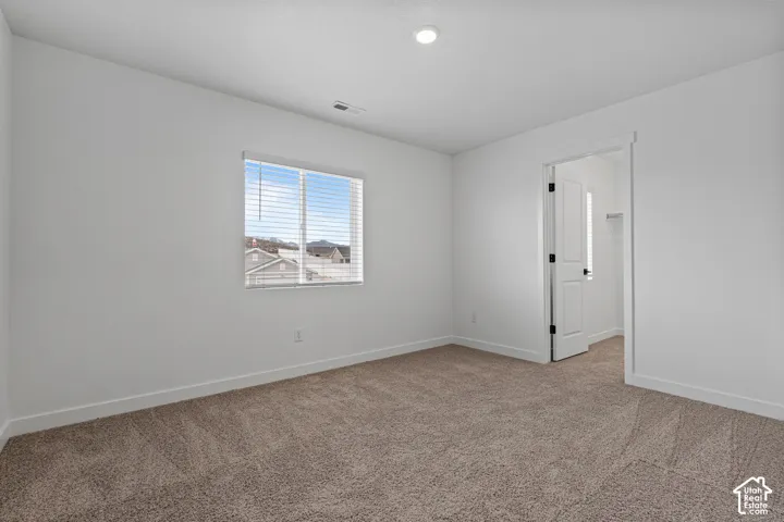 Plush carpeted flooring, a recessed ceiling light, and a white interior door with black hardware