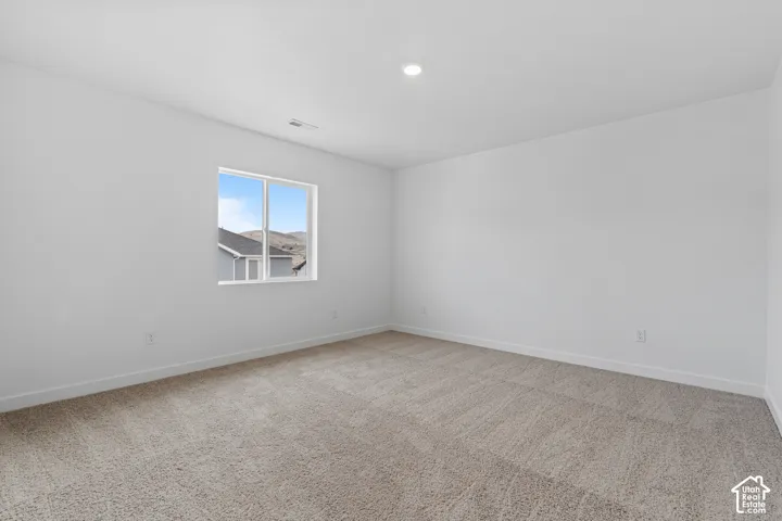 Recessed lighting, neutral-toned carpeting, white walls, and a large window