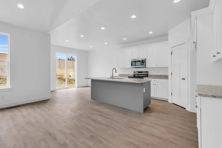Open-concept living space with wood-finish flooring, recessed lighting, and white walls