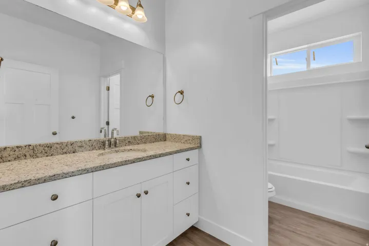 White vanity with brass hardware, light-toned countertop, and undermount sink