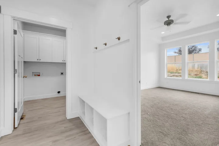 White cabinetry, wood-finish flooring, built-in bench with storage, ceiling fan, and large windows