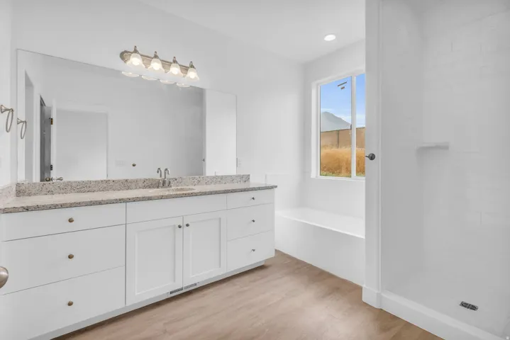 Dual-sink vanity with a light-toned countertop, large frameless mirror, and a five-light fixture