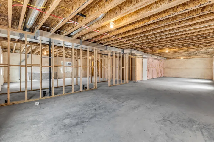 Unfinished basement with concrete flooring, exposed wood framing, and visible ductwork