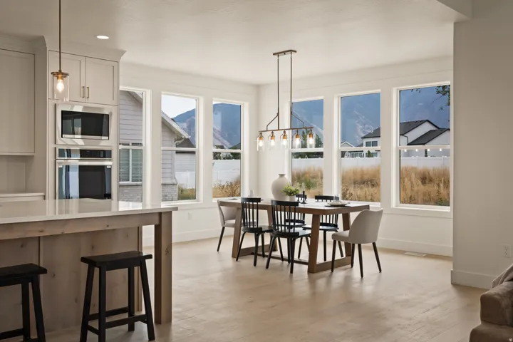 Built-in stainless steel appliances, light wood-finish flooring, multiple windows, and a linear chandelier