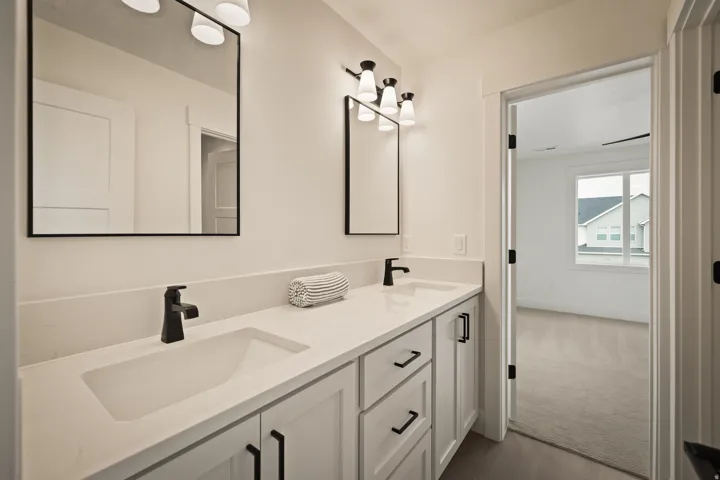 Jack and Jill double vanity featuring white cabinetry, integrated sinks, and matte black fixtures