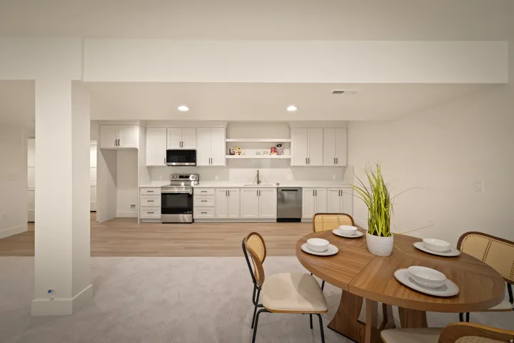 White cabinetry with stainless steel appliances, quartz countertops, and wood-finish flooring