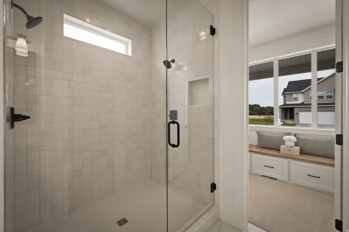 Glass-enclosed shower with subway tile surround, built-in niche, and transom window