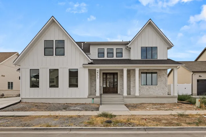 Modern farmhouse exterior featuring white vertical siding and light-colored stone accents