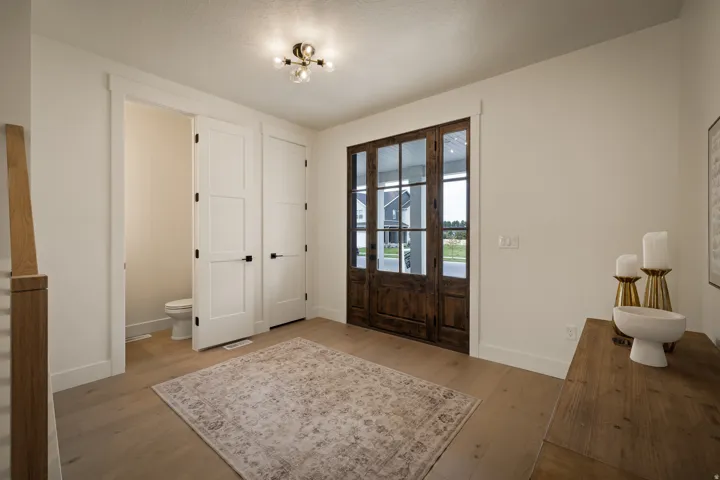Main entryway includes wood-finish flooring throughout, with a rustic wood-paneled glass-paneled entry door