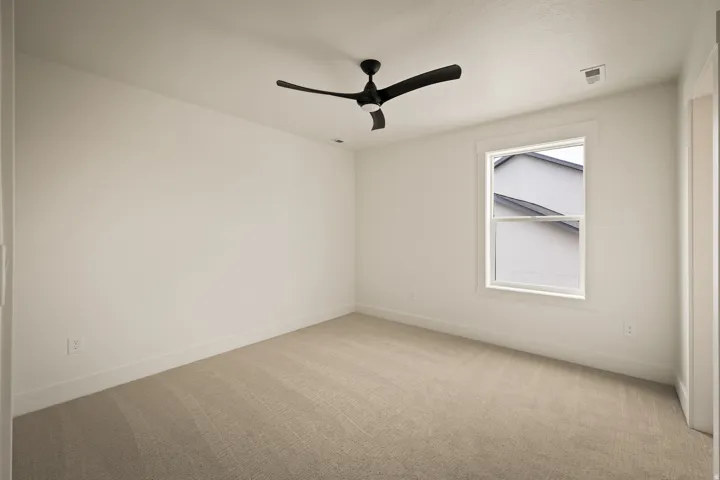 Neutral-toned carpet flooring, white walls, and a single window with white trim