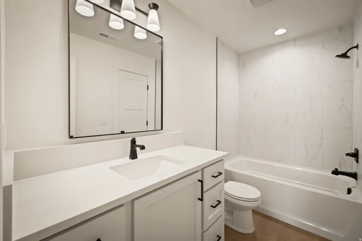 White vanity with an integrated sink, matte black faucet, and white countertop