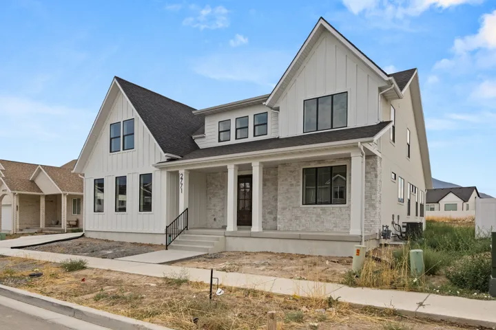 Modern farmhouse exterior with white board and batten siding, stone facade accents, dark framed windows, a covered entry, and a dark shingle roof