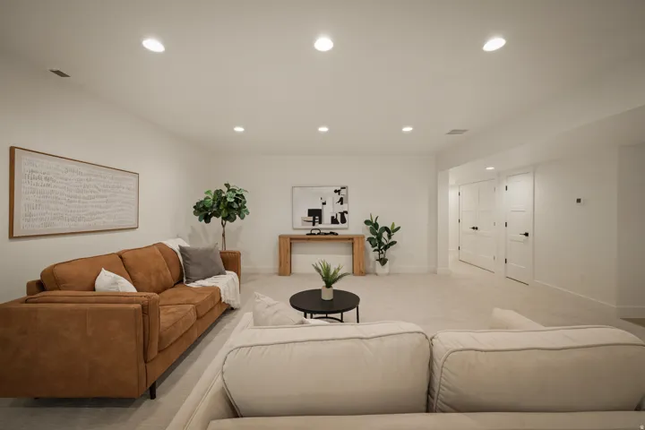 Recessed lighting throughout, light-toned carpeting, white walls, and multiple panel doors with dark hardware
