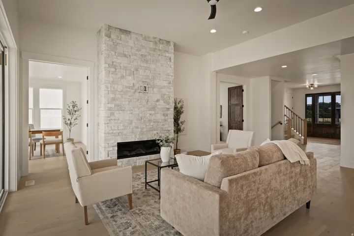 Main floor features stone-clad fireplace with a linear insert, wood-finish flooring, recessed lighting, and a modern ceiling fan