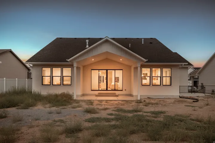 Rear exterior with covered patio, sliding glass doors, multiple windows, and a dark shingle roof