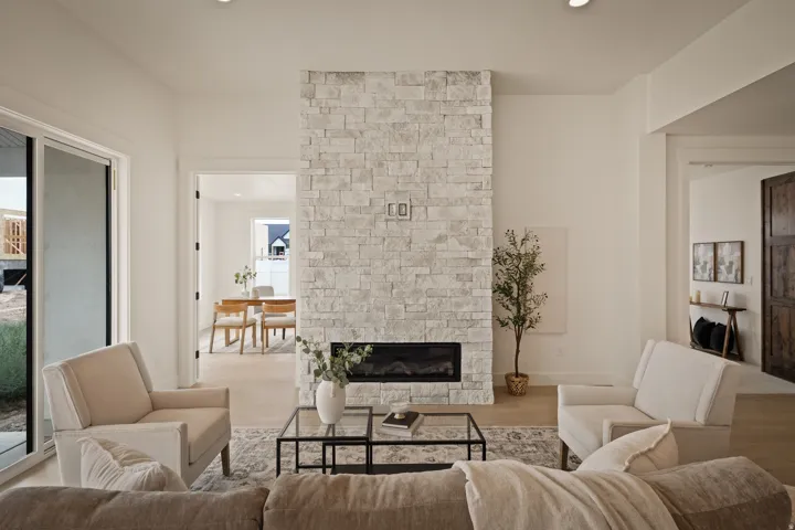 Stone-clad fireplace with an electric insert, recessed lighting, light wood-finish flooring, and a sliding glass door