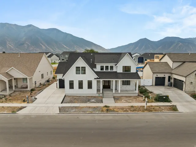 Contemporary farmhouse style residence with dark-framed windows, a covered front porch, a two-car garage, and a concrete driveway