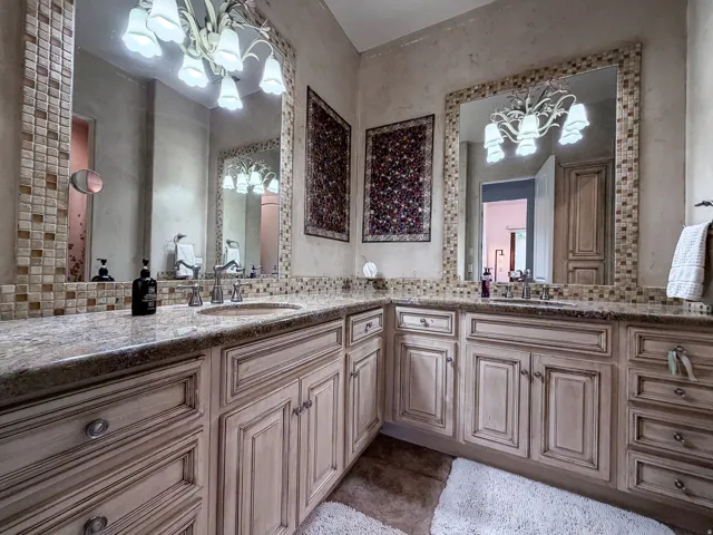 Dual vanity with wood-finish cabinetry, under-mount sinks, and decorative hardware