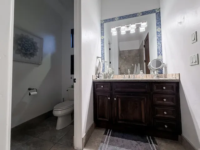 Dark wood-finish vanity with ample storage, integrated sink, and stone-finish countertop