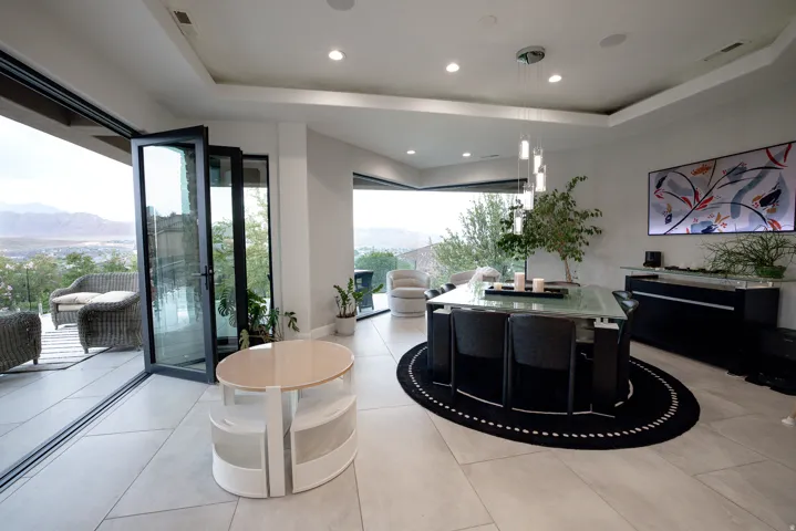 Expansive accordion glass doors, recessed lighting, tray ceiling, and light-toned tile flooring