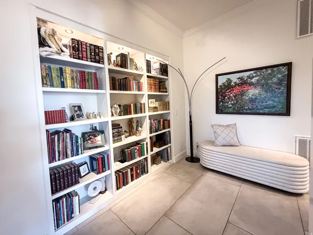Built-in shelving with recessed lighting, crown molding, and large-format tile flooring