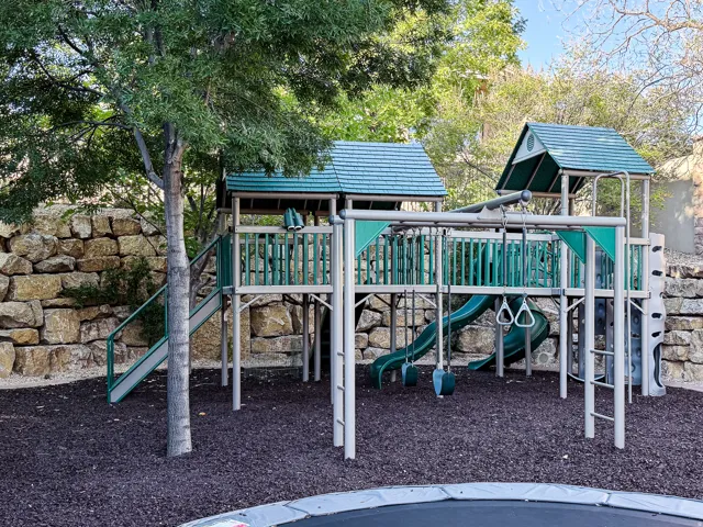 Outdoor play structure featuring multiple slides, swings, and climbing elements