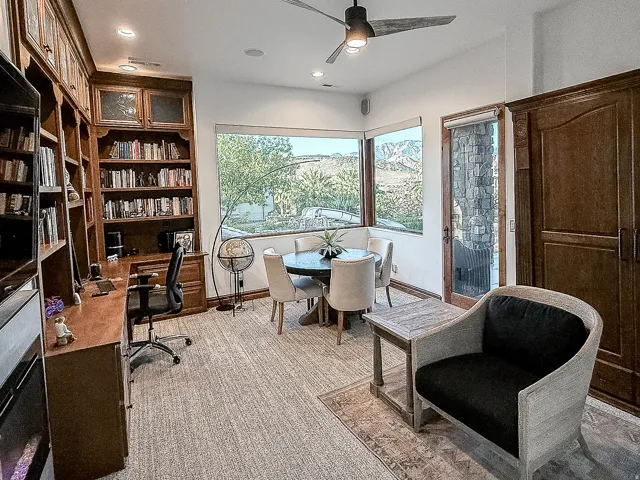 Built-in wood cabinetry with glass-front display, large bay windows, recessed lighting, and a ceiling fan with integrated lighting