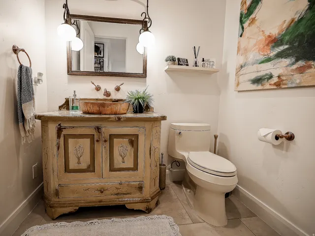 Distressed wood-finish vanity with an integrated vessel sink and wall-mounted faucet