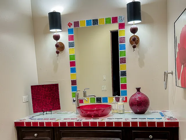 Vanity with a glass vessel sink, mosaic tile countertop, and sconce lighting