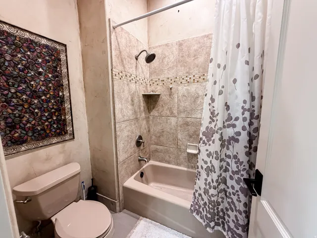 Built-in bathtub with a tile surround, mosaic accent tile, and a recessed shower niche