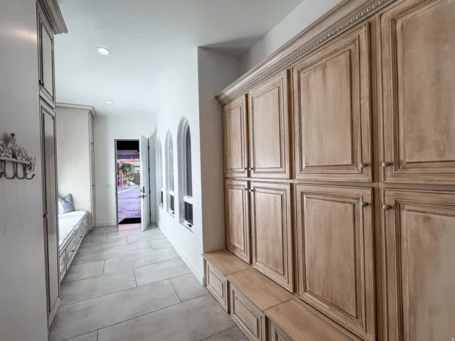 Built-in cabinetry with decorative crown molding and hardware, arched window accents, recessed lighting, and tile flooring