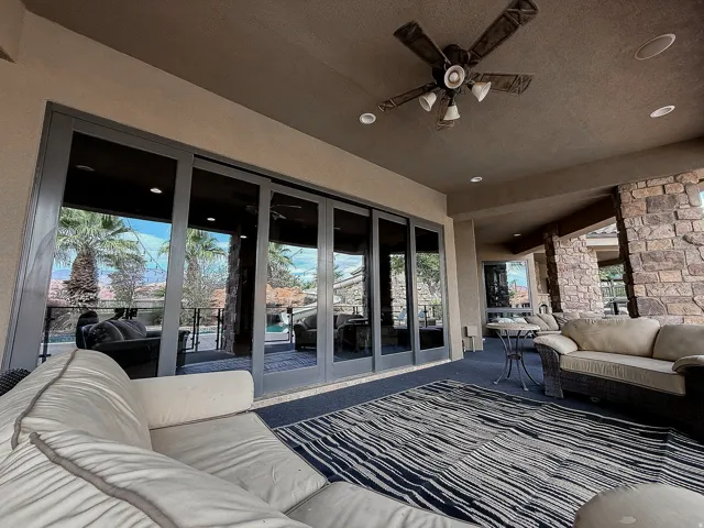 Covered outdoor patio featuring a ceiling fan with integrated lighting, recessed lighting, and a stone accent wall