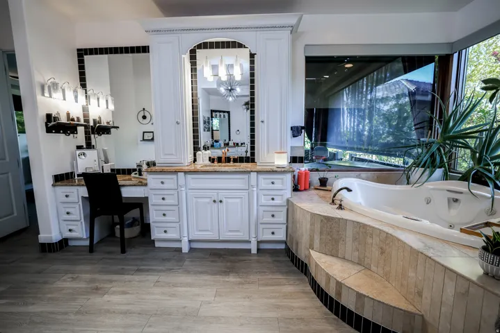 Built-in vanity with granite-style countertop, integrated makeup desk, dual mirrors, and wood-finish flooring