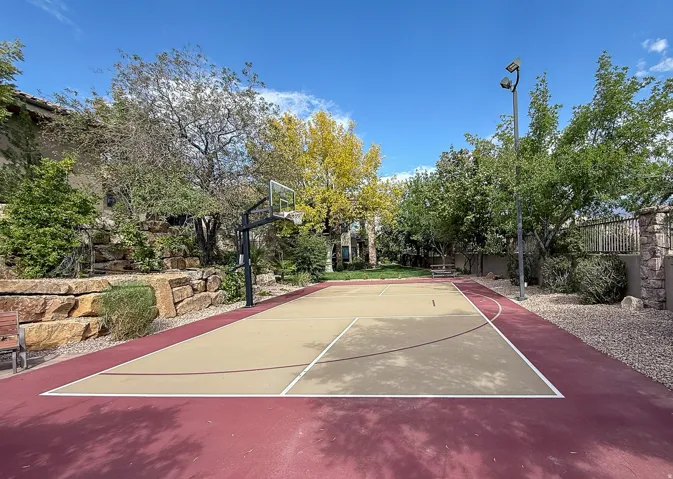 Sport court with a painted surface, basketball hoop, and perimeter lighting