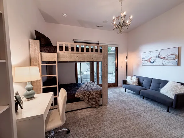 Vaulted ceiling with chandelier, built-in bunk beds, built-in shelving, wood-finish flooring, and glass-paneled patio door