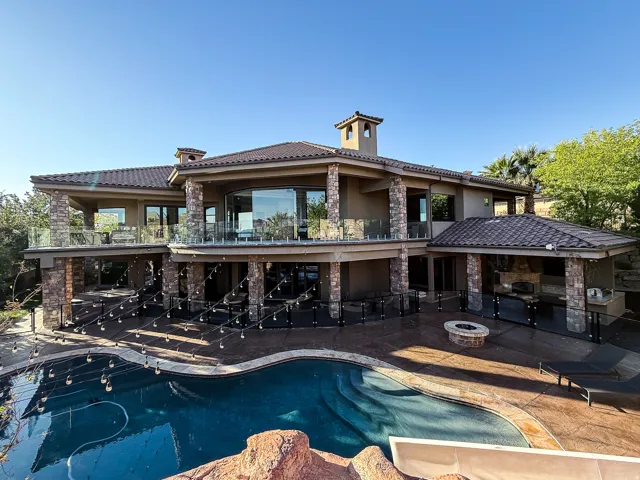 Multi-level stucco exterior with stone accents, a multi-tiered tile roof, and extensive glass railings