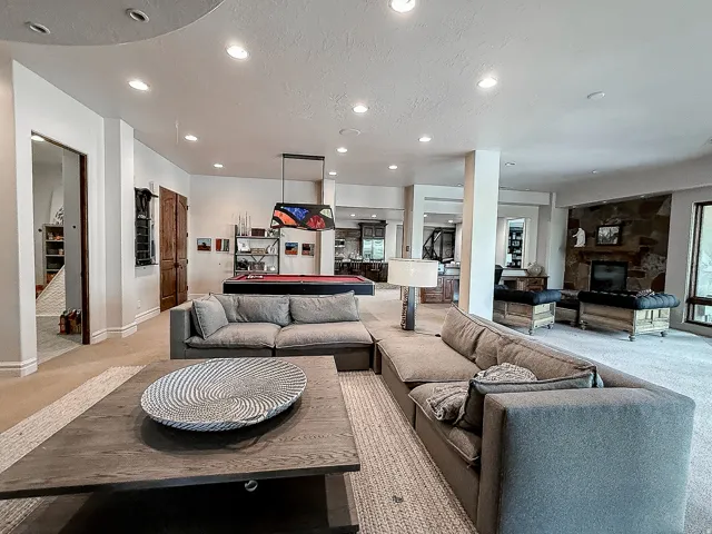 Spacious living area featuring recessed lighting, a stone-faced fireplace, and built-in shelving