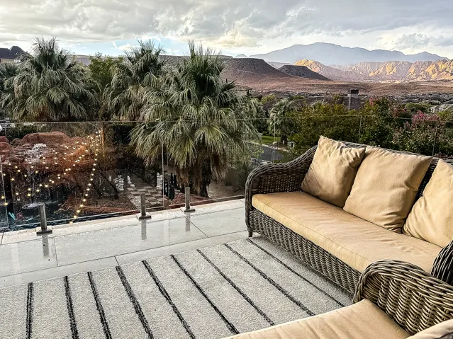 Expansive outdoor terrace featuring a glass railing, a water feature with integrated lighting, and mature palm trees