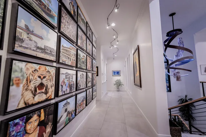 Spacious hallway featuring light-toned flooring, recessed lighting, track lighting, and a contemporary spiral chandelier