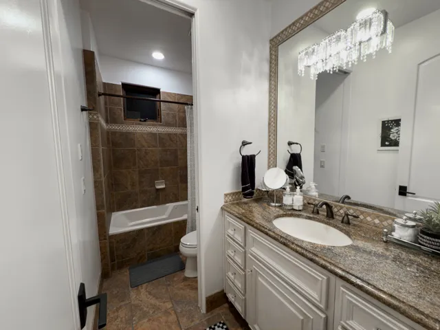 White vanity with panel detailing, stone countertop, undermount sink, and dark bronze faucet