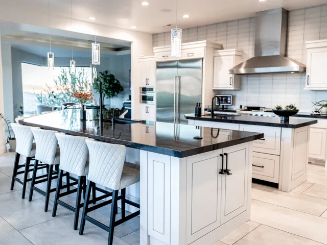 Gourmet kitchen with stainless steel appliances, dual islands with dark countertops, white cabinetry, and recessed lighting
