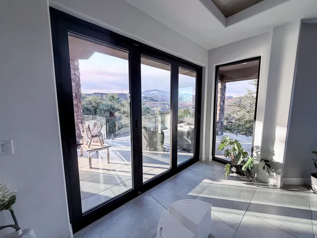 Expansive glass wall with black frames, offering a wide exterior landscape with distant mountains