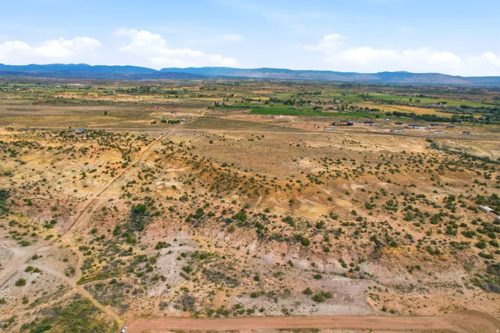 Expansive arid landscape with scattered green vegetation, distant agricultural fields, and a prominent mountain range