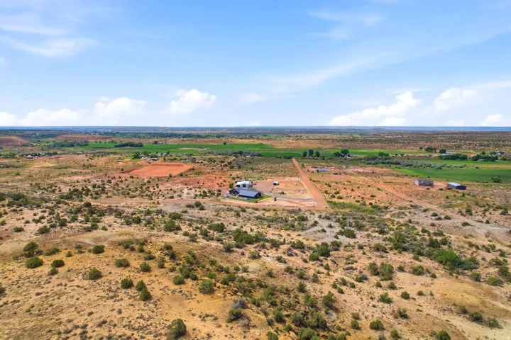 Expansive acreage with scattered vegetation and distant green fields