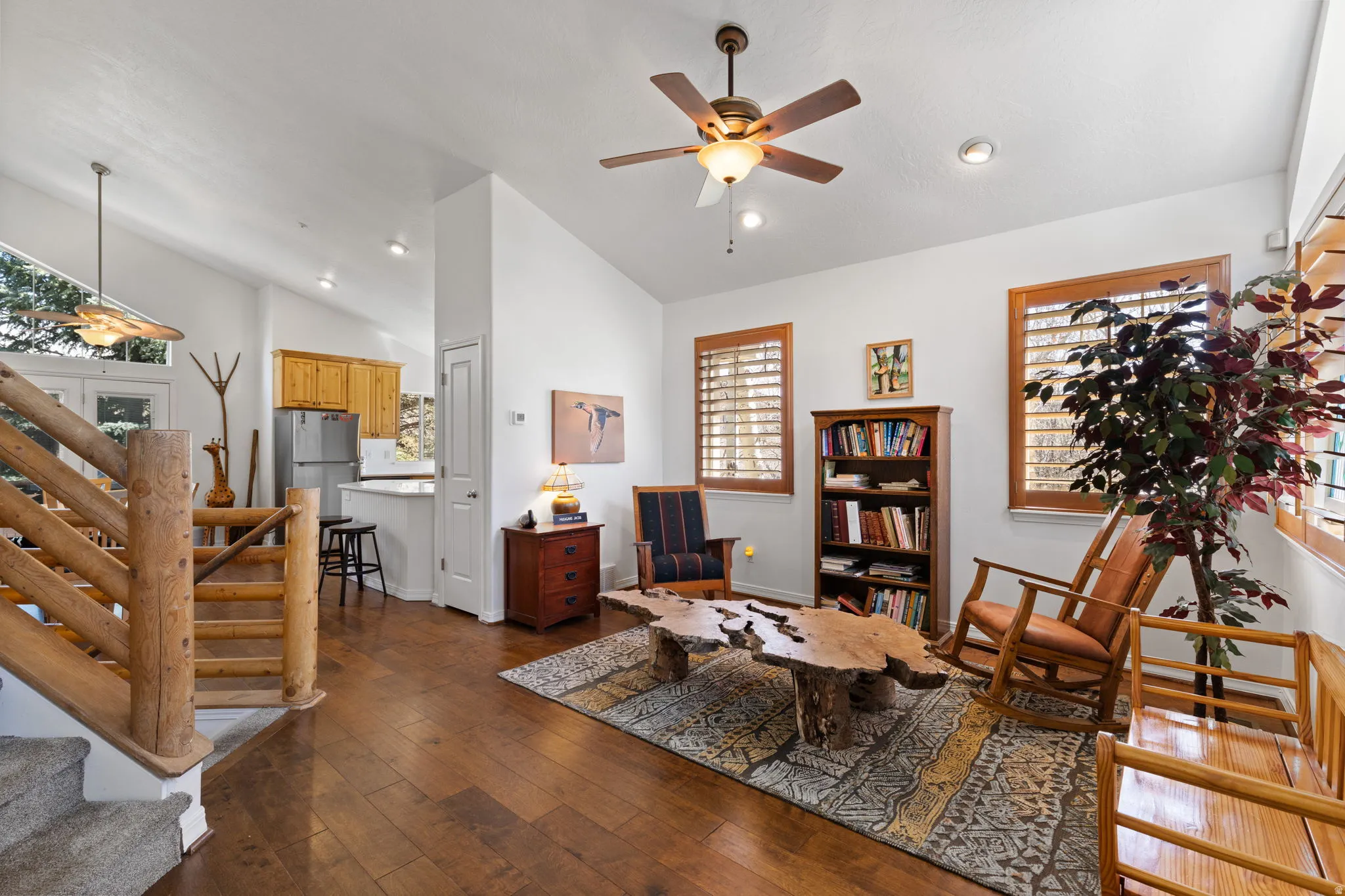 Living area featuring wood-finish flooring, vaulted ceilings, and a ceiling fan