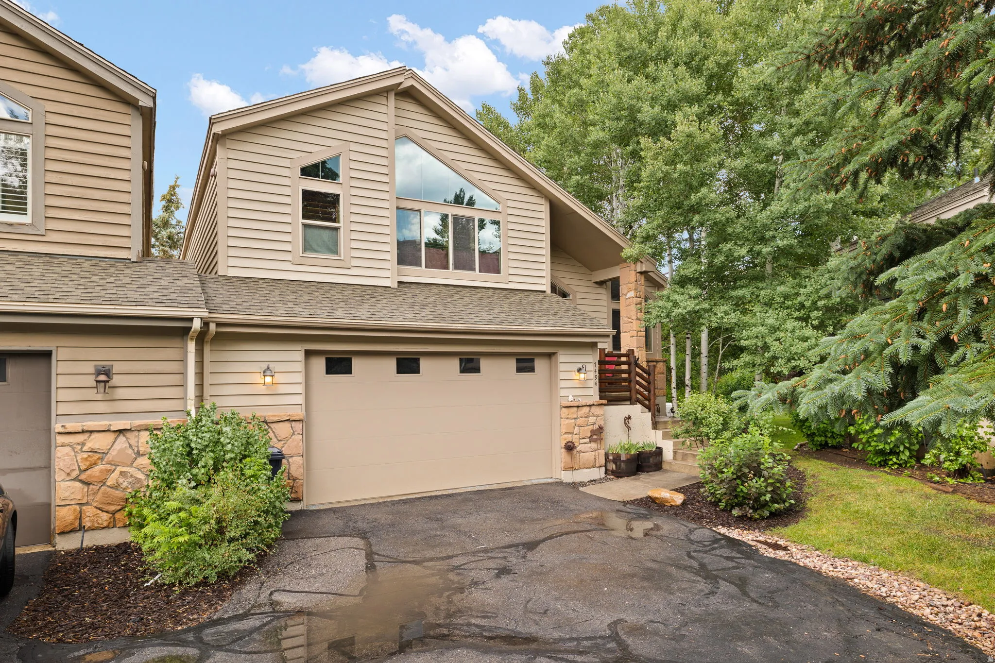 Tan siding exterior with stone accents and a two-car garage