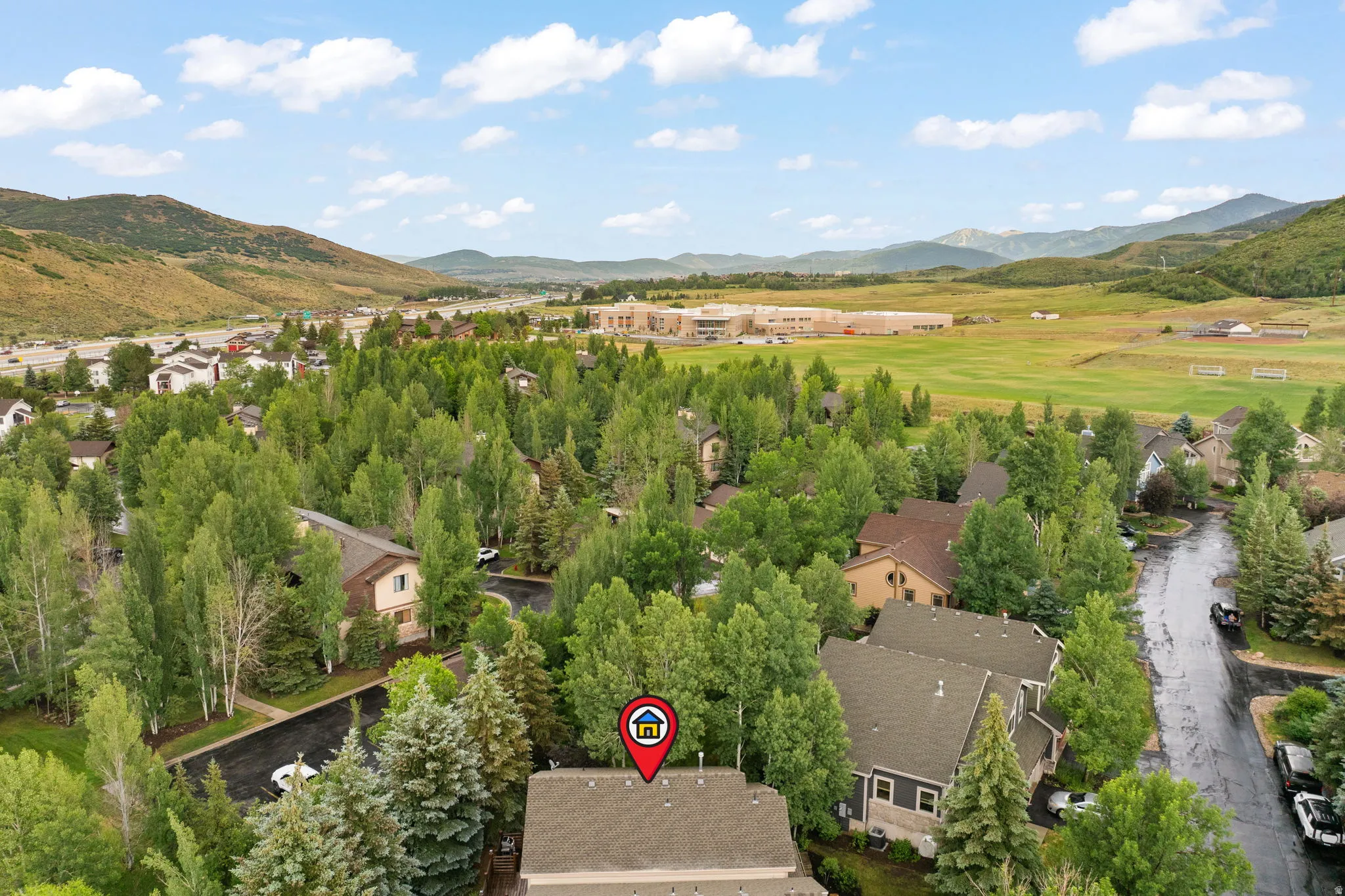 Aerial perspective showcasing a residential area surrounded by abundant mature trees and mountainous terrain