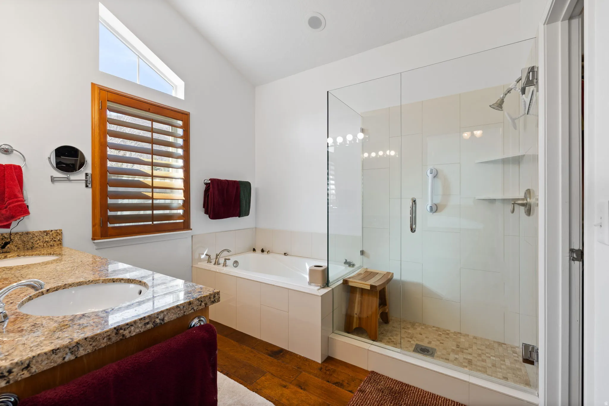 Bathroom featuring a glass-enclosed shower with pebble-tile flooring, a built-in tub, and a vanity with a granite countertop and integrated sink
