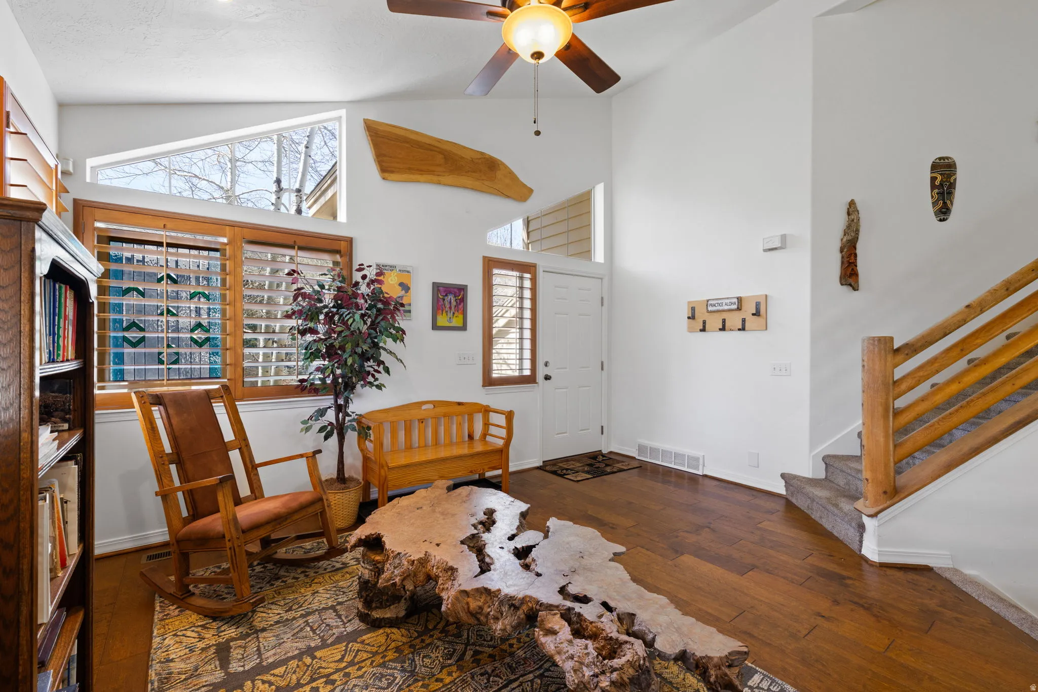 Vaulted ceiling with a wood-finish ceiling fan, wood-finish flooring, and white walls