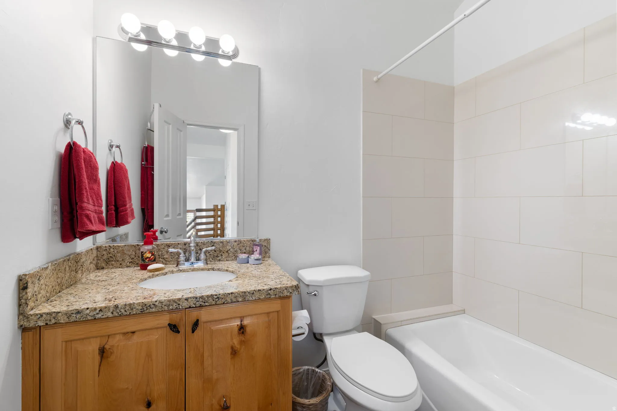 Bathroom featuring a wood-finish vanity with a granite-look countertop and an integrated sink